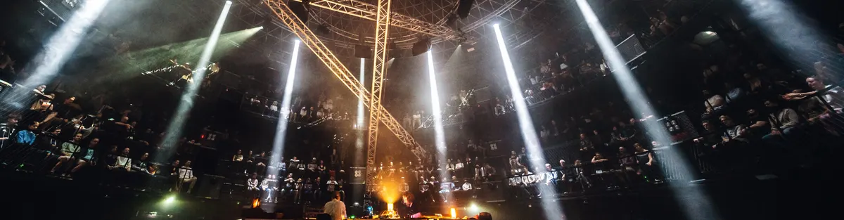Beams of light crossing a hall in the round above the audience