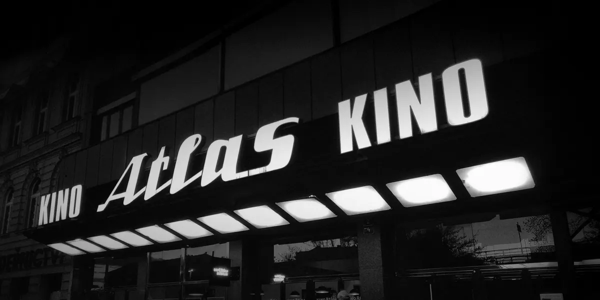 The lit Kino Atlas sign over the cinema's entrance at night